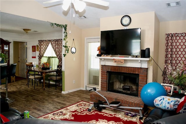 living room with lofted ceiling, dark wood-type flooring, a brick fireplace, and visible vents