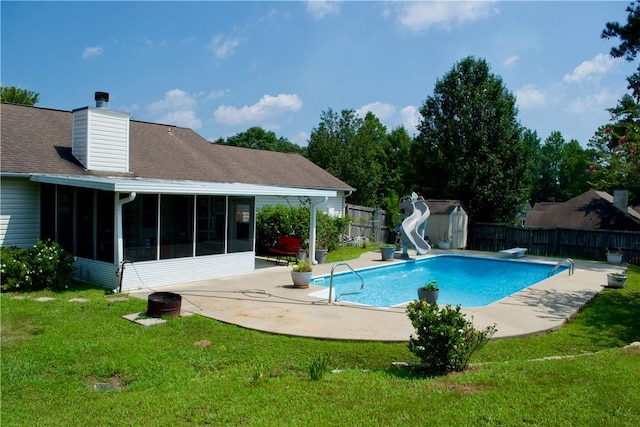 view of pool featuring a storage unit, a lawn, a sunroom, a water slide, and a fenced backyard