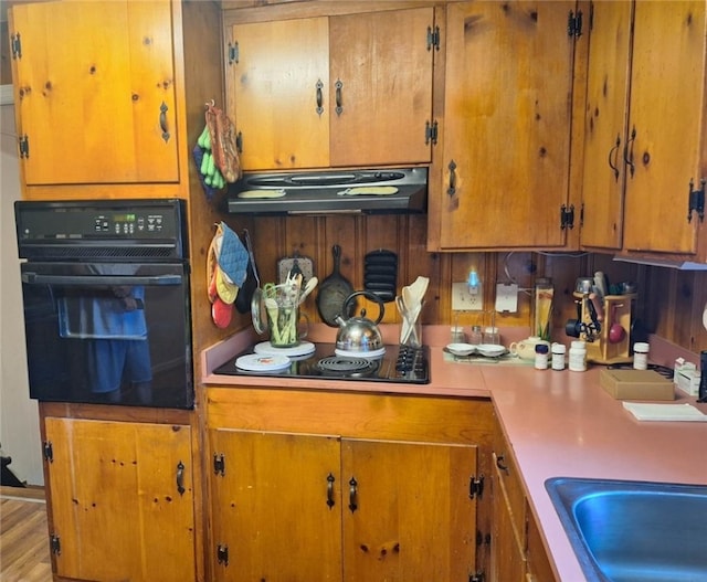 1701 53rd St, Valley, AL 36854 - kitchen with black appliances, under cabinet range hood, brown cabinetry, and light countertops