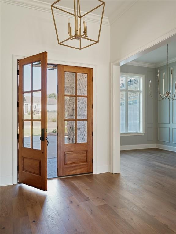 foyer entrance featuring a chandelier, ornamental molding, and wood-type flooring