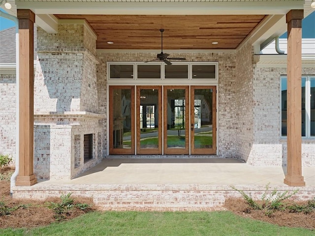 doorway to property featuring a brick fireplace, a patio, and ceiling fan