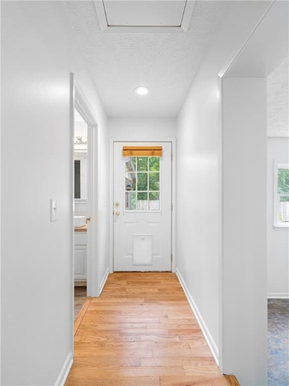 doorway to outside featuring light wood-type flooring and a textured ceiling