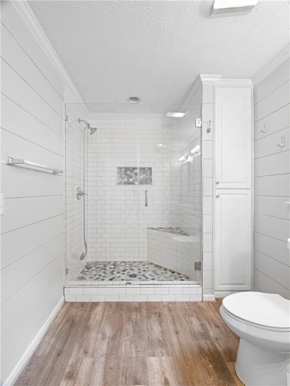 bathroom featuring a textured ceiling, hardwood / wood-style flooring, an enclosed shower, and ornamental molding