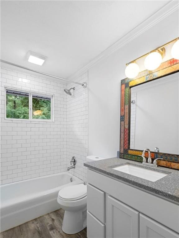 full bathroom featuring ornamental molding, vanity, tiled shower / bath combo, hardwood / wood-style flooring, and toilet