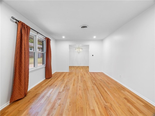 unfurnished room with light wood-type flooring and an inviting chandelier