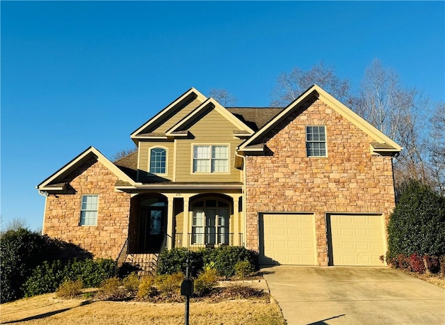 craftsman-style home featuring a garage, stone siding, and concrete driveway