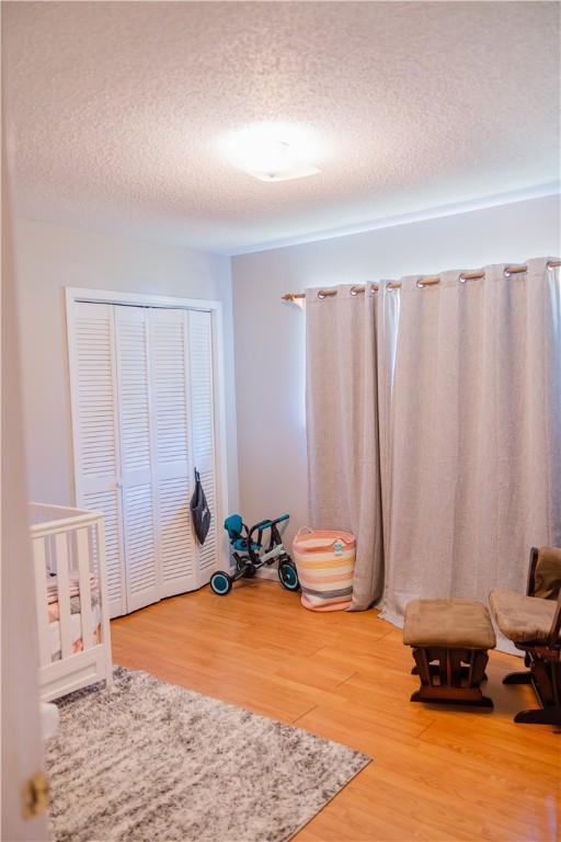 2401 11th Ave, Valley, AL 36854 - unfurnished bedroom featuring a textured ceiling, light wood finished floors, and a closet