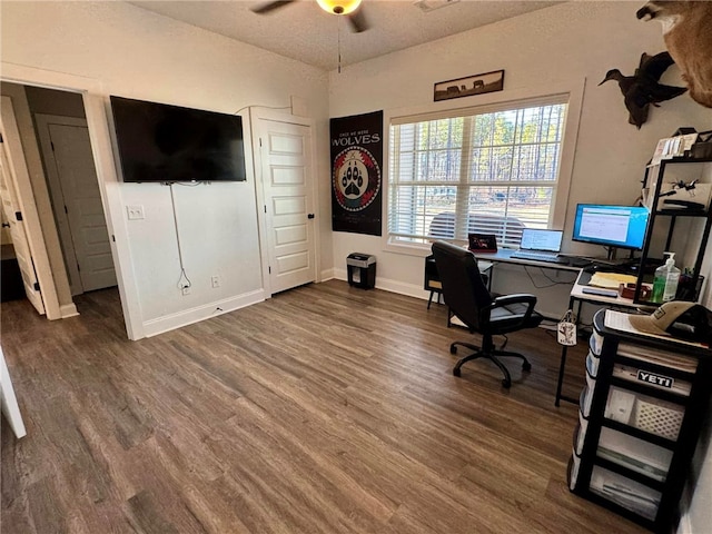 home office with ceiling fan and dark hardwood / wood-style flooring