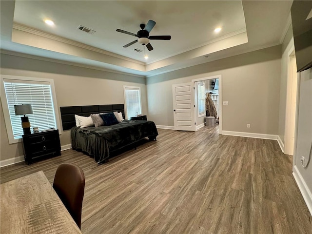 bedroom with hardwood / wood-style flooring, ceiling fan, a raised ceiling, and ornamental molding