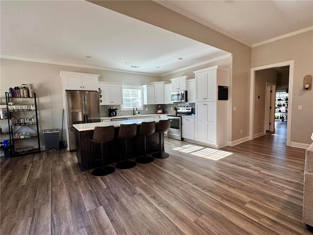 kitchen with a kitchen island, white cabinetry, stainless steel appliances, and a breakfast bar area