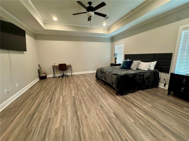 bedroom featuring hardwood / wood-style floors, ceiling fan, a raised ceiling, and ornamental molding