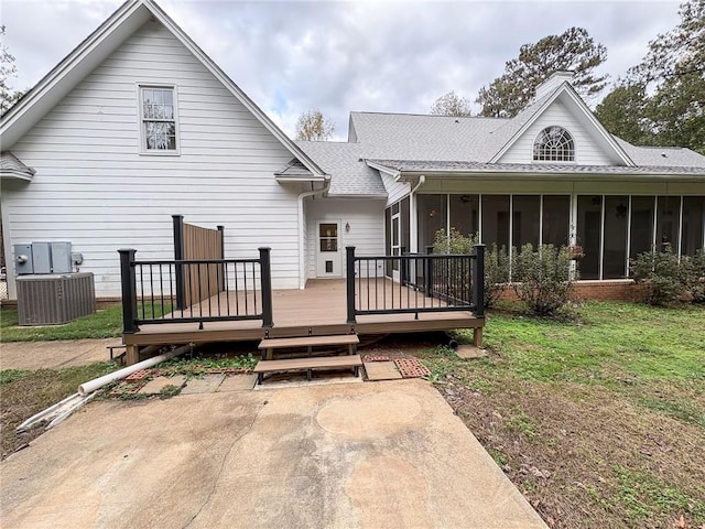 view of front facade with a wooden deck, a sunroom, central AC unit, and a front yard