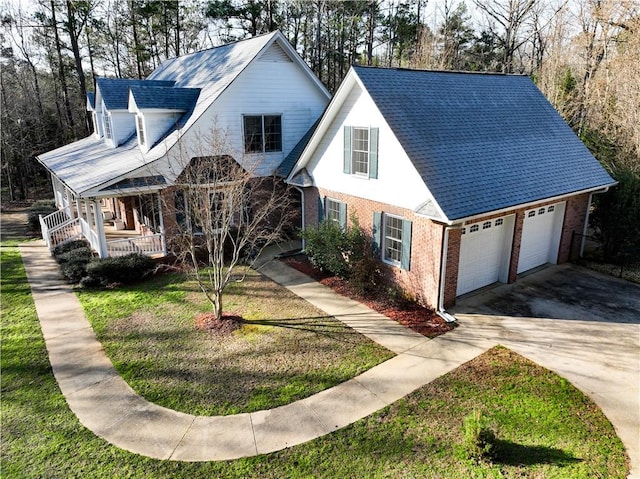 view of front of home featuring brick siding, a porch, an attached garage, a front yard, and driveway