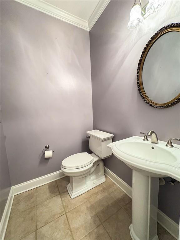 bathroom featuring tile patterned floors, crown molding, and toilet