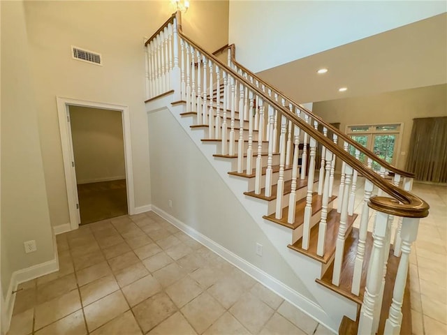 staircase with tile patterned flooring and a high ceiling