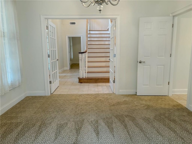 empty room featuring light colored carpet, french doors, and a chandelier