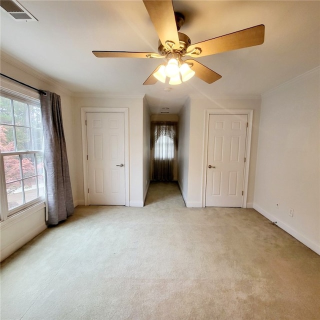 unfurnished bedroom with ceiling fan, light colored carpet, and crown molding