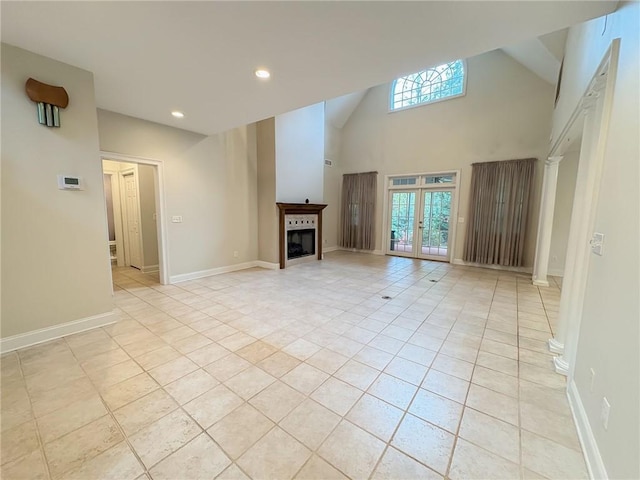 unfurnished living room with a towering ceiling, french doors, and light tile patterned flooring