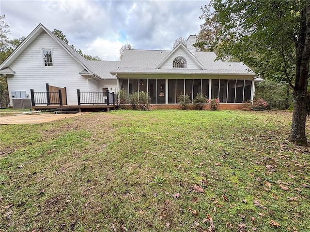 rear view of property featuring a lawn, a wooden deck, and a sunroom