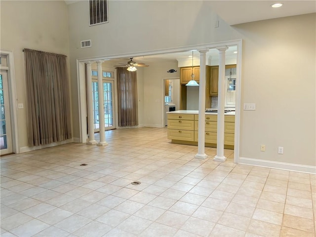 tiled empty room with ceiling fan and a high ceiling