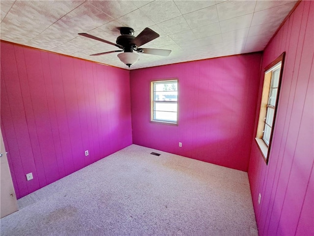 735 Willow St, Alexander City, AL 35010 - spare room featuring carpet flooring, ceiling fan, visible vents, and wood walls