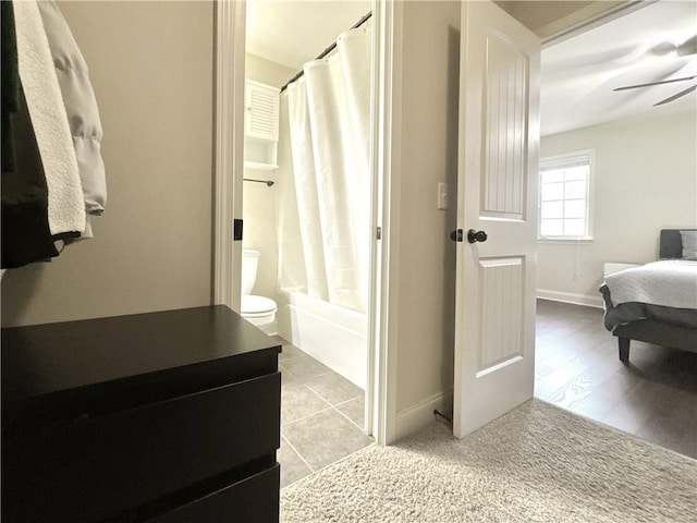 bathroom featuring toilet, tile patterned flooring, shower / tub combo with curtain, baseboards, and ceiling fan