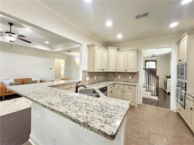 kitchen with appliances with stainless steel finishes, a sink, a peninsula, crown molding, and a ceiling fan