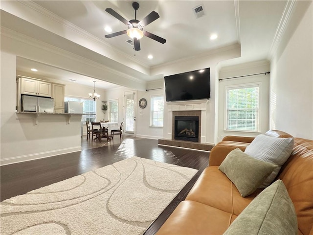 living room with dark wood-style flooring, healthy amount of natural light, ceiling fan, a fireplace, and ornamental molding