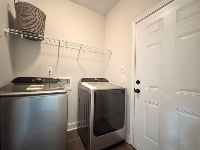 washroom featuring washing machine and dryer, dark tile patterned floors, and baseboards