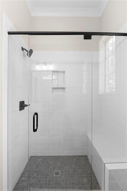 bathroom with a shower with door and crown molding