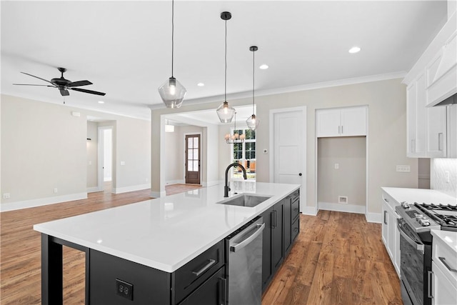 kitchen with stainless steel appliances, ceiling fan, a kitchen island with sink, sink, and decorative light fixtures