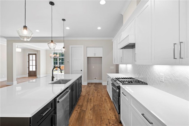 kitchen with appliances with stainless steel finishes, a kitchen island with sink, sink, decorative light fixtures, and white cabinets