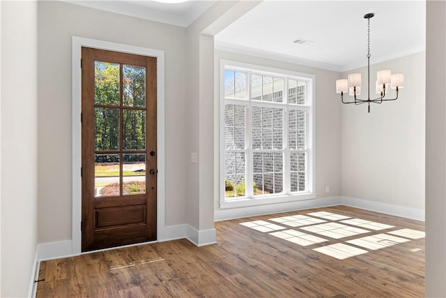 entryway with hardwood / wood-style floors, a notable chandelier, and crown molding