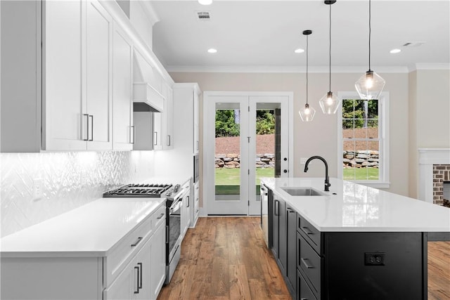 kitchen with pendant lighting, a center island with sink, white cabinets, sink, and appliances with stainless steel finishes