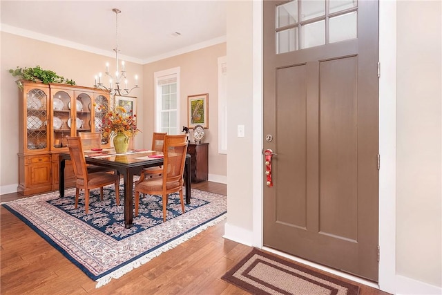 dining area with a notable chandelier, ornamental molding, baseboards, and wood finished floors