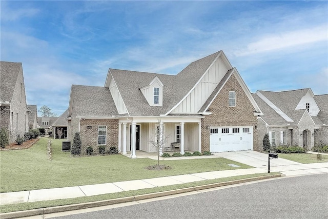 view of front of property featuring brick siding, board and batten siding, a shingled roof, a front yard, and driveway