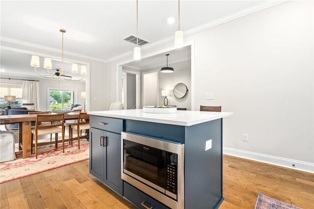 2402 Furlong Trl, Auburn, AL 36830 - kitchen with stainless steel microwave, light wood-type flooring, ornamental molding, pendant lighting, and light countertops