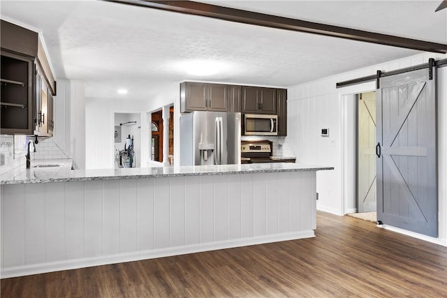 2 Lakewood Cir, Phenix City, AL 36867 - kitchen featuring stainless steel appliances, a barn door, dark wood-style floors, and decorative backsplash