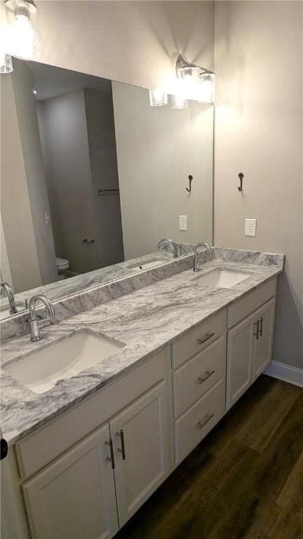 full bathroom featuring double vanity, wood finished floors, toilet, and a sink
