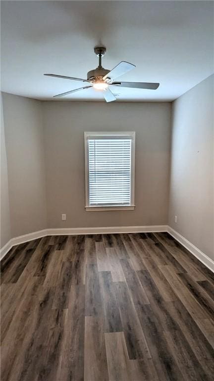 empty room featuring dark wood-style floors, a ceiling fan, and baseboards