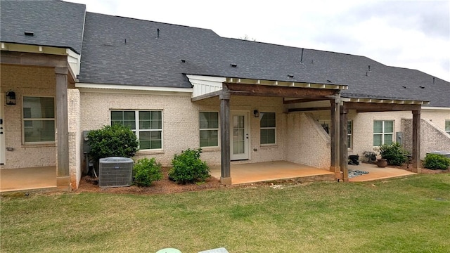 back of property featuring a patio, a lawn, a shingled roof, and central AC unit