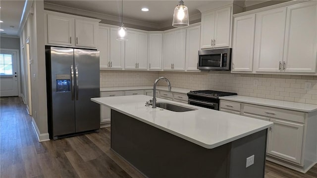 kitchen featuring a sink, appliances with stainless steel finishes, ornamental molding, dark wood-type flooring, and a kitchen island with sink