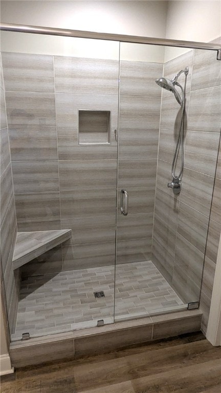 bathroom with wood finished floors and a shower stall