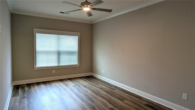 spare room featuring crown molding, visible vents, baseboards, dark wood-type flooring, and a ceiling fan