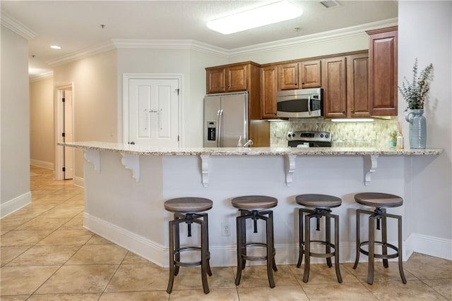 kitchen featuring a breakfast bar area, kitchen peninsula, light stone countertops, and stainless steel appliances