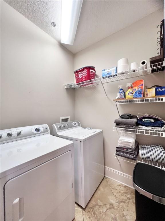 laundry area featuring a textured ceiling and washing machine and clothes dryer