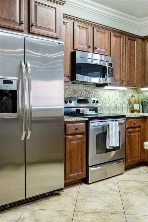 kitchen featuring backsplash, stainless steel appliances, ornamental molding, and light tile patterned flooring