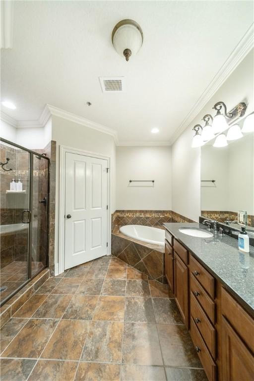 bathroom featuring vanity, ornamental molding, and independent shower and bath