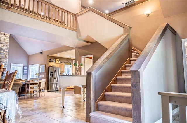 stairs with tile patterned flooring and high vaulted ceiling