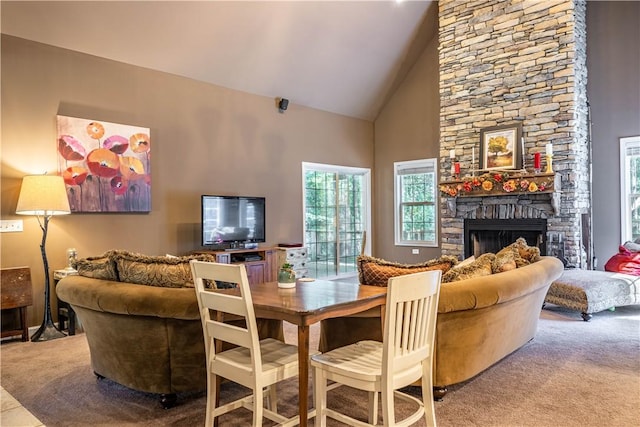 dining area with carpet flooring, high vaulted ceiling, and a stone fireplace